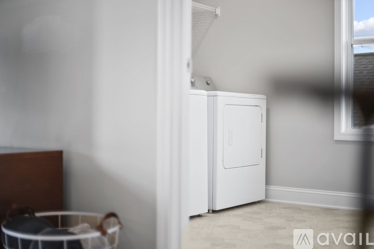 A white refrigerator is in a room with a basket on the floor.