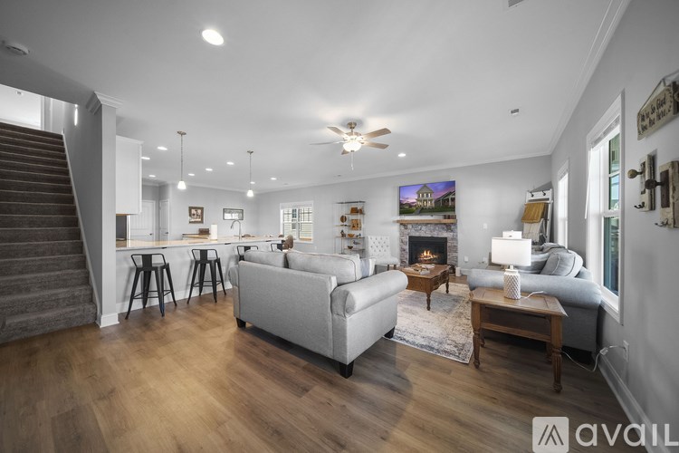 A spacious living room with a staircase on the left side and a couch in the center.