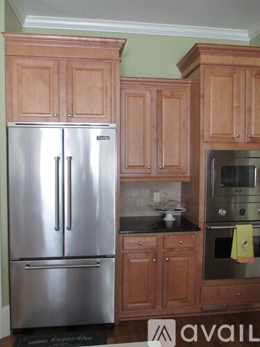 A kitchen with wooden cabinets and a stainless steel refrigerator.