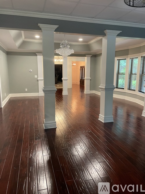 A spacious room with wooden floors and white columns.