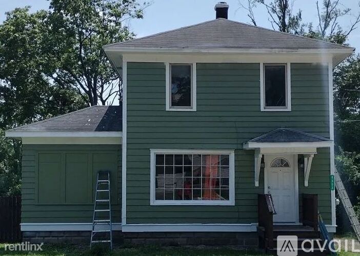 A green house with a white door and windows.
