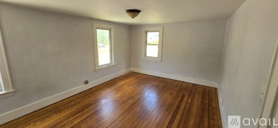A room with wooden floors and two windows.