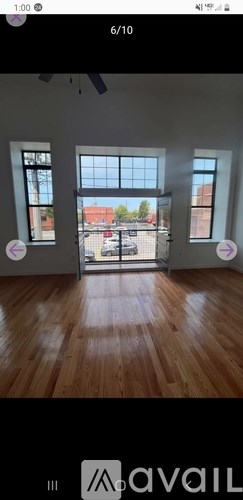 A room with wooden flooring and a view of a parking lot through a glass door.