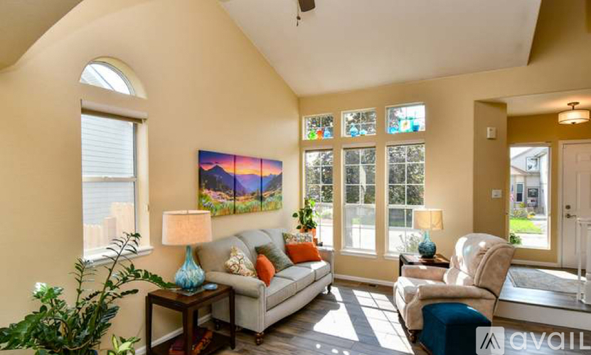A living room with a couch, a chair, a table with a lamp and a painting on the wall.