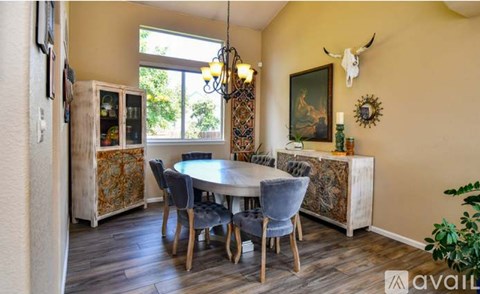 A dining room with a table set for six and a chandelier hanging from the ceiling.
