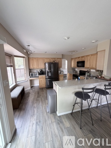 A kitchen with wooden cabinets and a white island with two stools.
