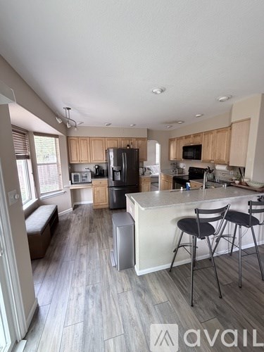 A kitchen with wooden cabinets and a white island with two stools.