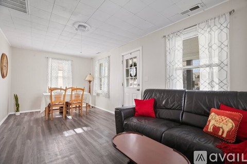 A living room with a black leather couch and a wooden chair.