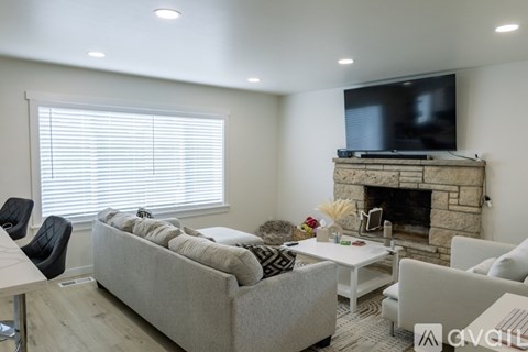 A living room with a grey couch, a white coffee table, a fireplace, and a television mounted above it.