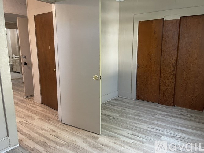 A room with a white door and wooden floor.