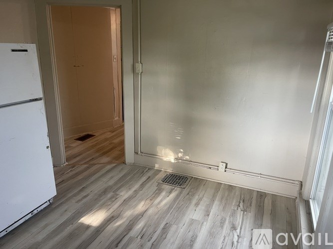 A kitchen with a white fridge and wooden floors.