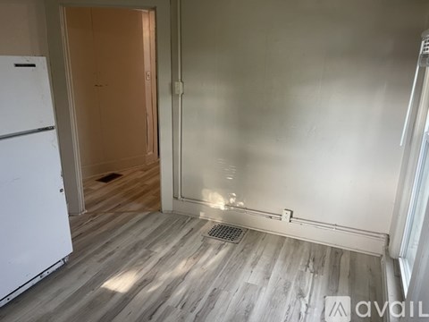 A kitchen with a white fridge and wooden floors.