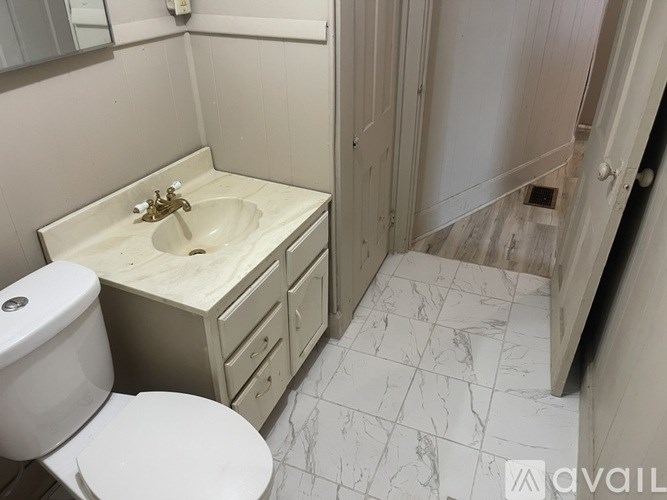 A bathroom with a toilet, sink, and marble floor.