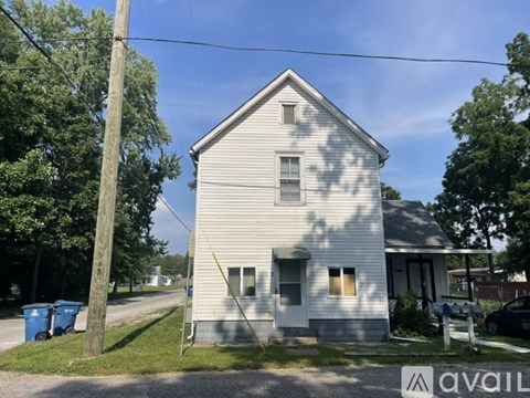A white house with a grey roof is for sale.