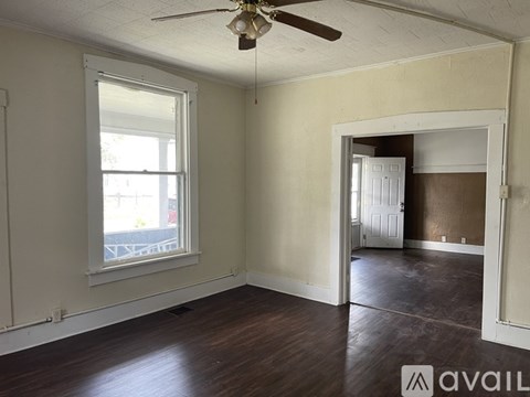 A room with a ceiling fan and a doorway leading to another room.