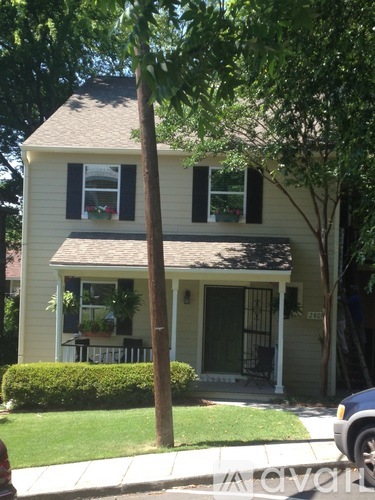 A house with a green lawn and a tree in front.
