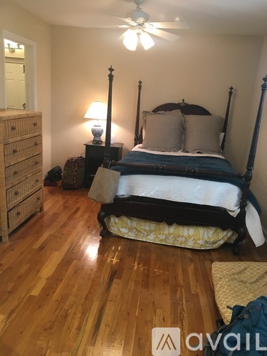 A bedroom with a bed, dresser, and ceiling fan.