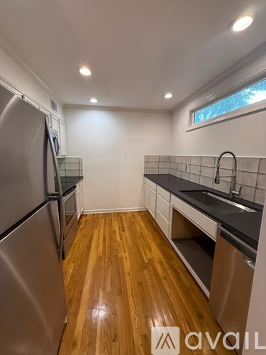 A kitchen with a stainless steel refrigerator and wooden floors.