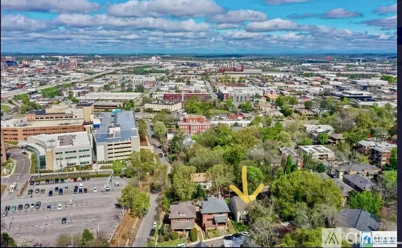 A yellow arrow points to a building in a city.