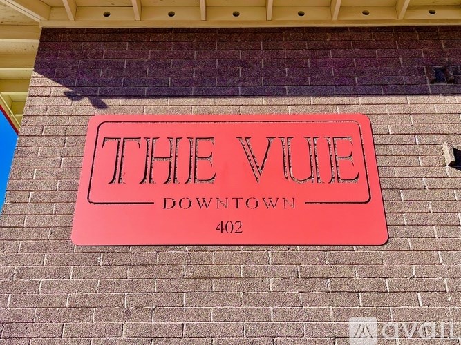 A red sign on a brick wall that says "The Vue Downtown 402".