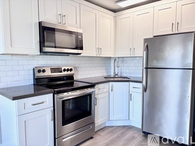 A kitchen with white cabinets and a stainless steel refrigerator.