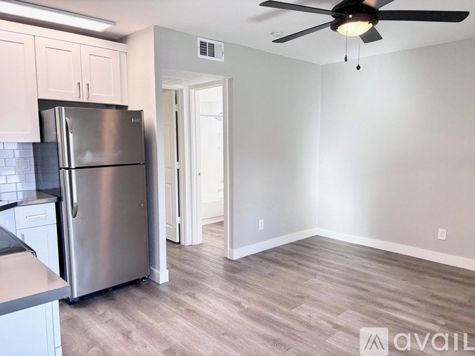 A kitchen with a refrigerator and a ceiling fan.