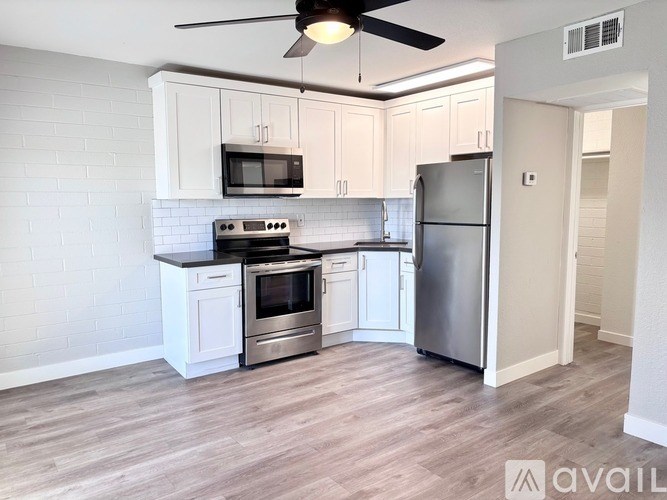 A kitchen with a refrigerator, microwave, oven, and cabinets.