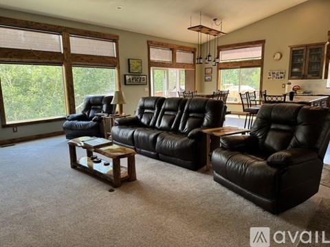 A living room with black leather furniture and a large window.