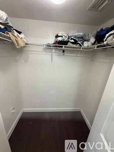 A small, white closet with a wooden floor and a metal shelf.