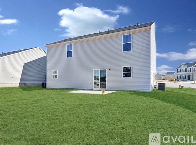A large white building with a grey roof and a green lawn in front.