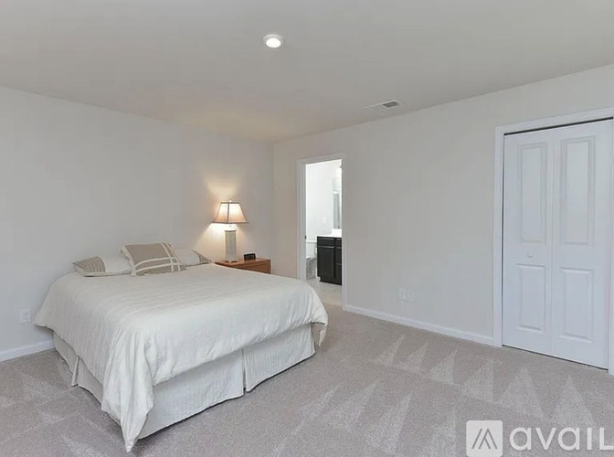A bedroom with a large bed and a lamp on the side table.