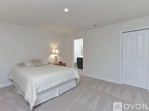 A bedroom with a large bed and a lamp on the side table.