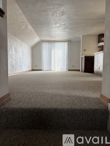 A carpeted room with a window covered by blinds.