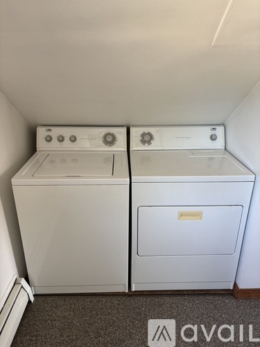 Two white front loading washing machines in a small room.