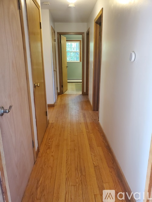 A long hallway with wooden floors and white walls.