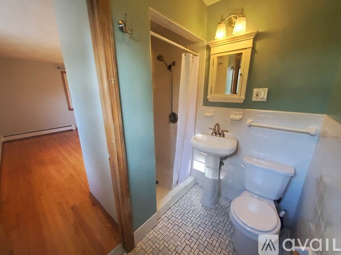 A bathroom with a toilet, sink, and mirror.