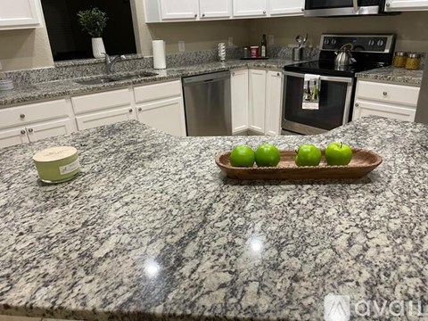 A kitchen counter with a tray of green apples on it.