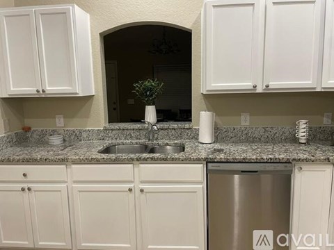 A kitchen with granite countertops and white cabinets.