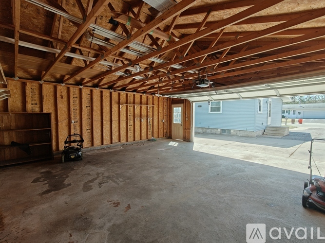 A spacious garage with wooden walls and ceiling, a concrete floor, and a small workbench.