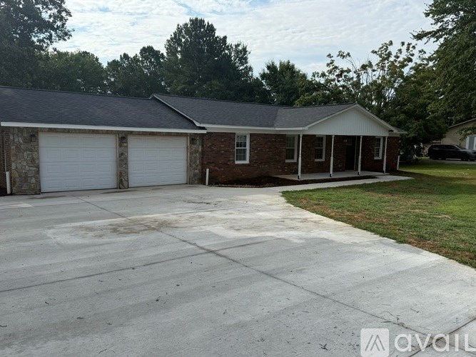 A two-car garage with a brick house and a white roof.