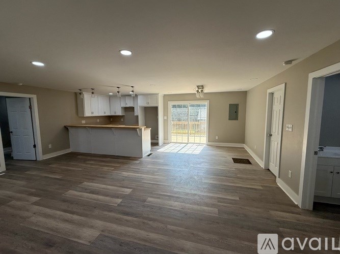 A spacious living room with a kitchen area in the background.