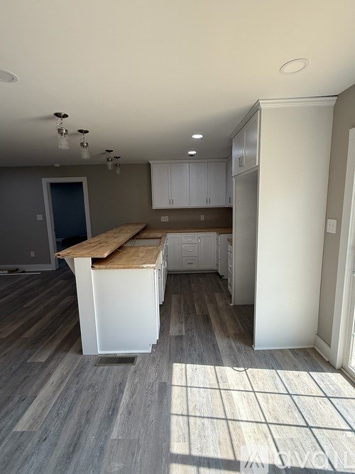 A kitchen with a white island and wooden countertop.