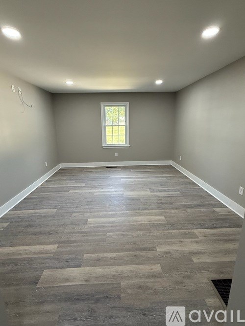 A room with wooden flooring and a window.