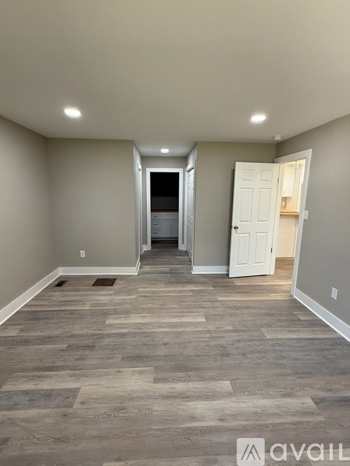 A hallway with a wooden floor and white walls.