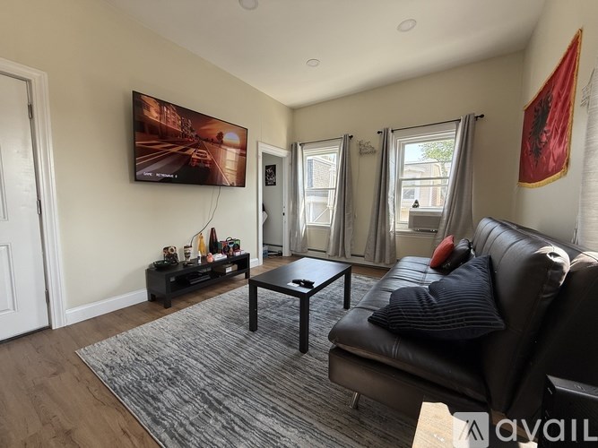 A living room with a black leather couch and a large painting on the wall.