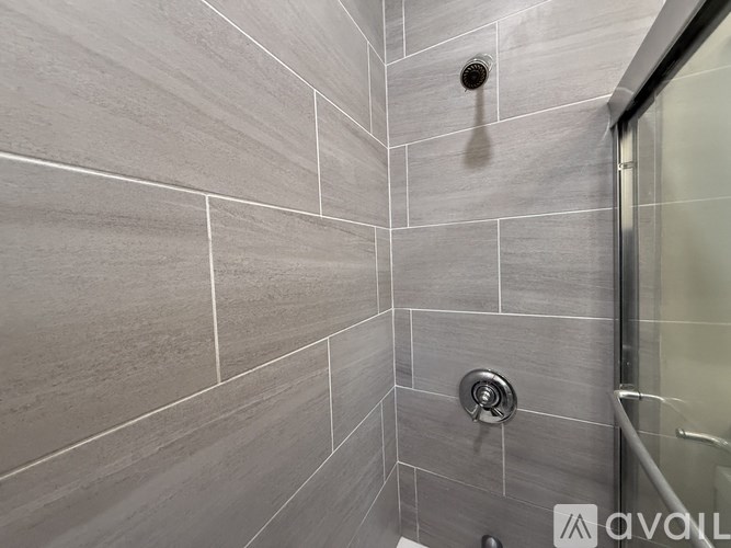 A modern bathroom with a shower head and a glass door.