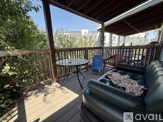 A balcony with a black leather couch, a round table, and a blue chair.