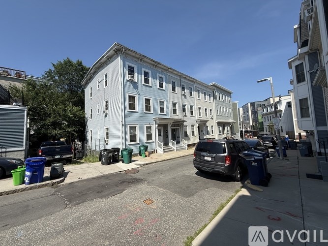 A street view of a blue building with cars parked in front.