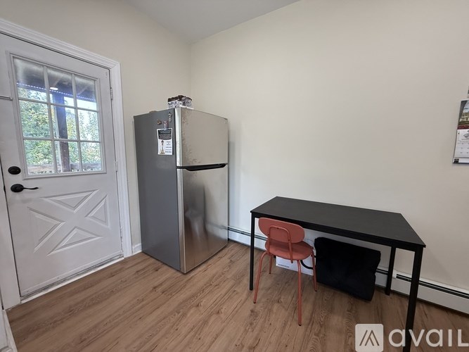A small room with a table, chairs and a fridge.