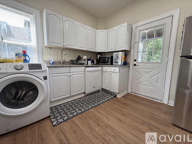 A small, clean, and well-organized kitchen with white cabinets and a washer and dryer.